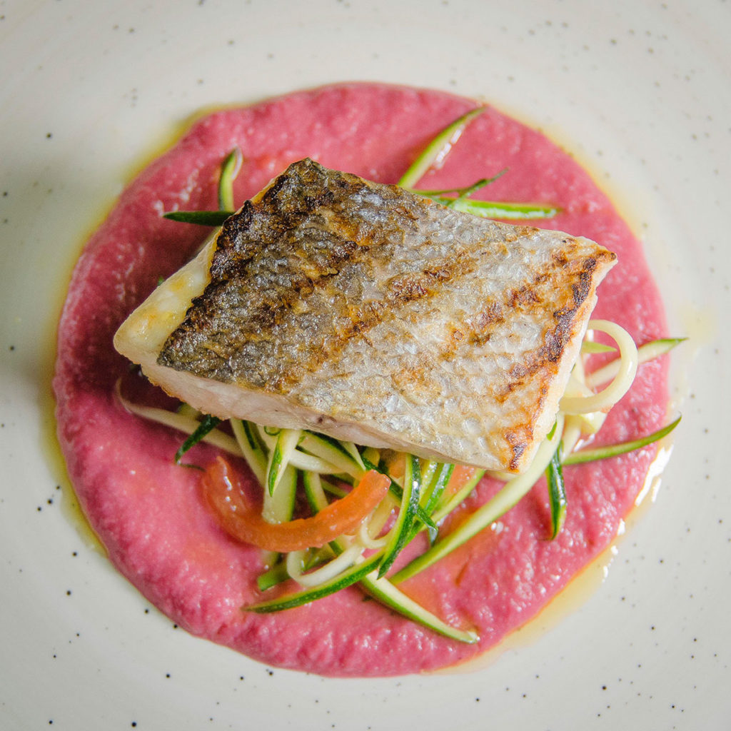 Spigola mediterranea grigliata, hummus alla bietola rossa, courgetti alla colatura di alici